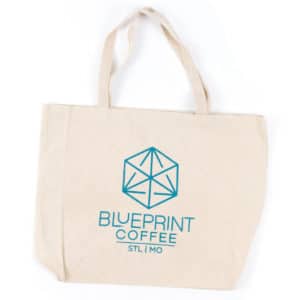 A canvas tote bag bearing the Blueprint Coffee vertical logo in "Blueprint" blue screen print.