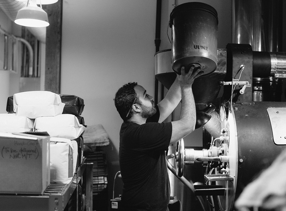Mazi Razani loads green, unroasted, coffee into the Gothot roaster at Blueprint Coffee.