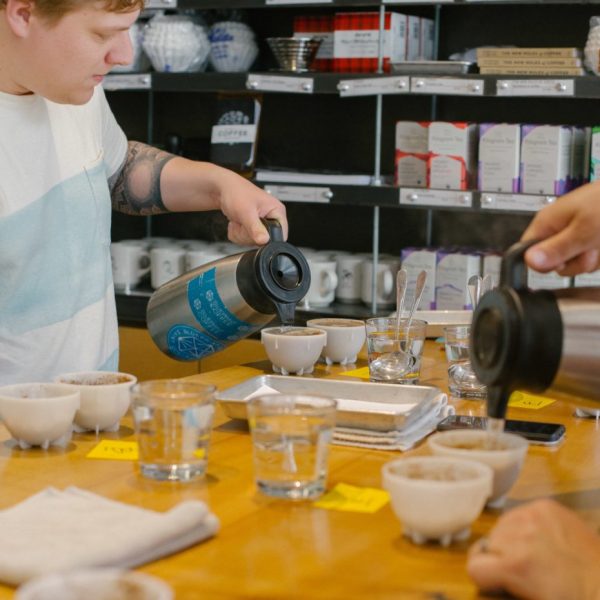 Blueprint staff pours water onto freshly ground coffee during a cupping.