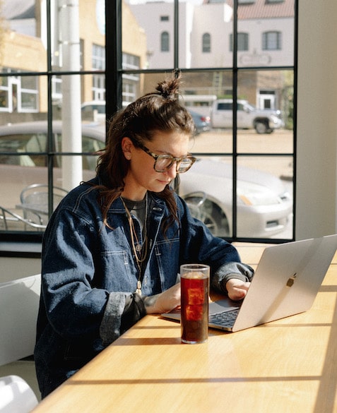 Nora Brady works on a computer at Blueprint Coffee's High Low location while drinking an iced coffee
