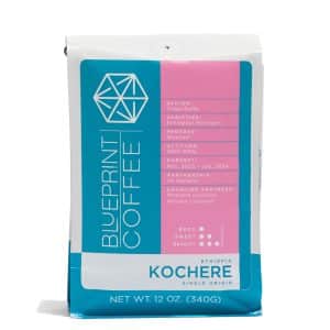 A 12-ounce bag of Kochere, Ethiopia coffee beans. It features the Blueprint Coffee logo on the left half and coffee details in pink on the right half.