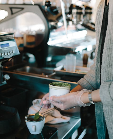 MG 6 The hands of a person dumping a spoonful of machta into a tea strainer