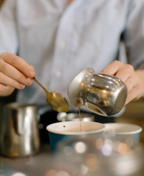 Mac pours syrup into a Blueprint Coffee to go cup.