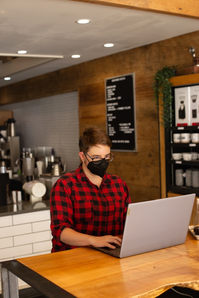 T works on their laptop at the wooden standing bar of our Delmar café