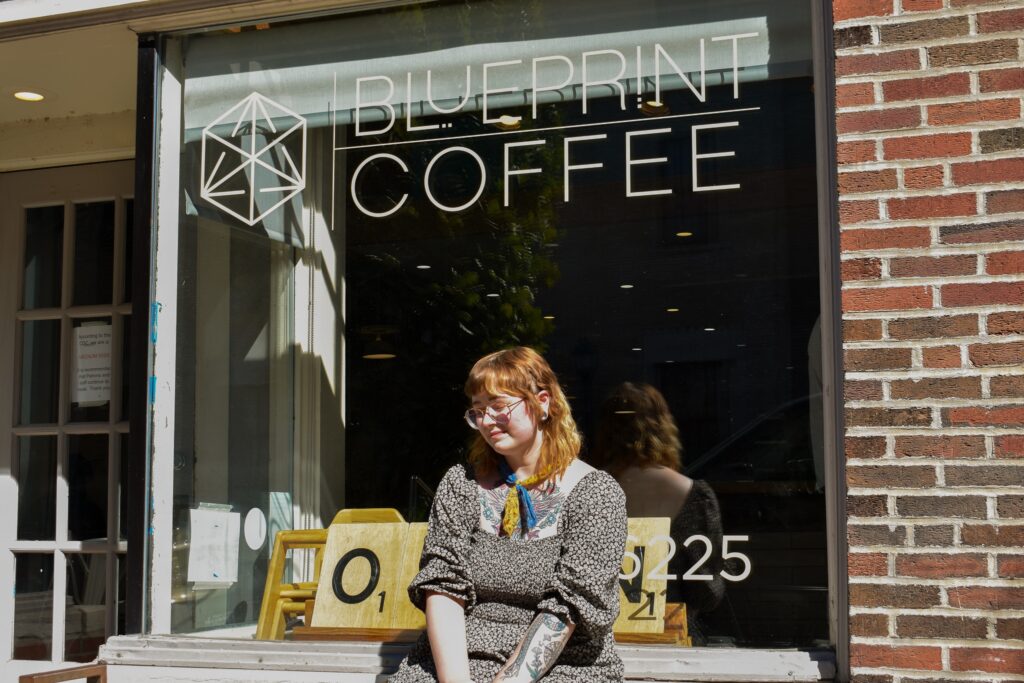 Ashley sits in the front window sill outside our Delmar café