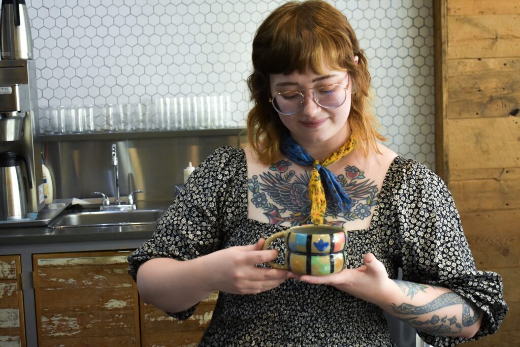 Ashley holds a beautiful ceramic mug that was handmade by her