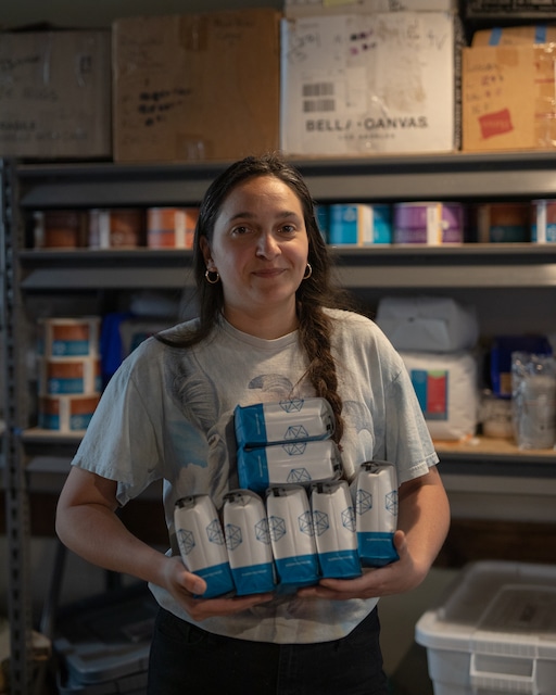 Marija holds an armful of retail coffee bags