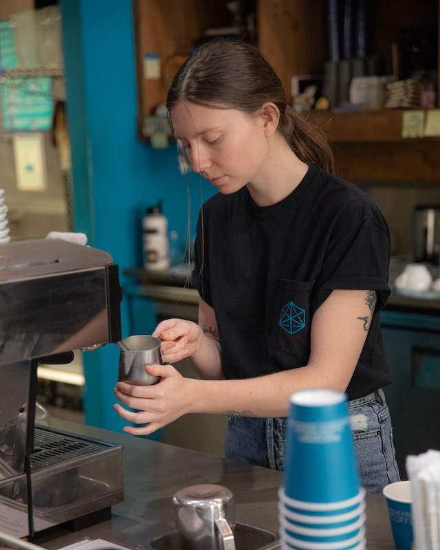Val behind the bar at our Delmar café, steaming milk to make a latte