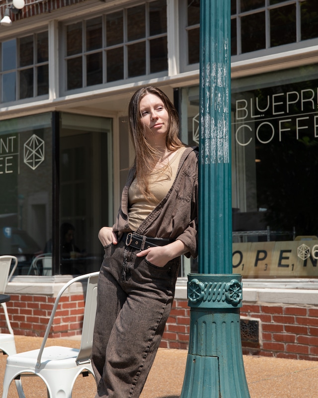 Val leans against a green light pole on the sidewalk in front of our Delmar café