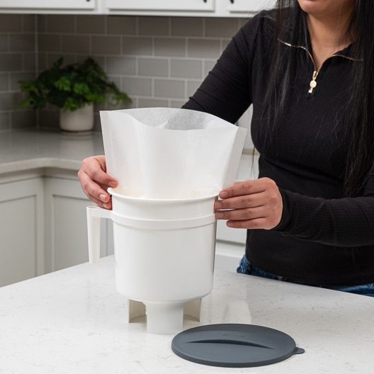 Image of person inserting Toddy OS Filter Bag into a brewing vessel.