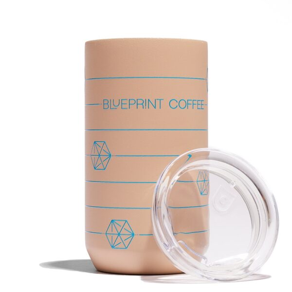 A 12-ounce sandy brown Blueprint Coffee "cube" tumbler against a white background. The tumbler is a sandy brown color with blue print. The lid rests against the side.