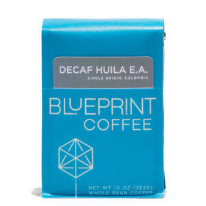 A blue 10-ounce bag of Decaf Huila EA, Colombia coffee beans featuring the Blueprint Coffee Logo and a removable info card.