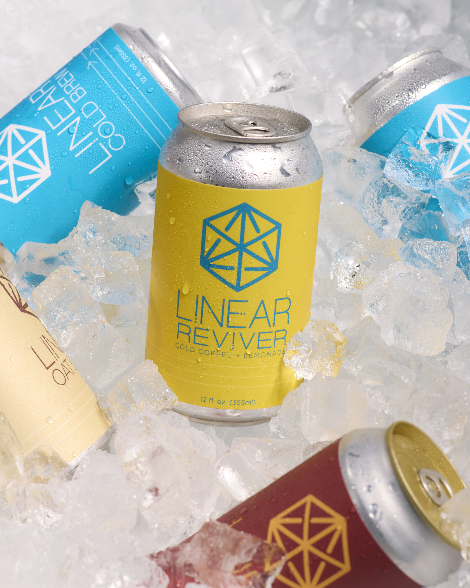 A can of Linear Reviver in a cooler full of ice surrounded by cans of Linear Cold Brew, Chai Soda, and Oat Latte