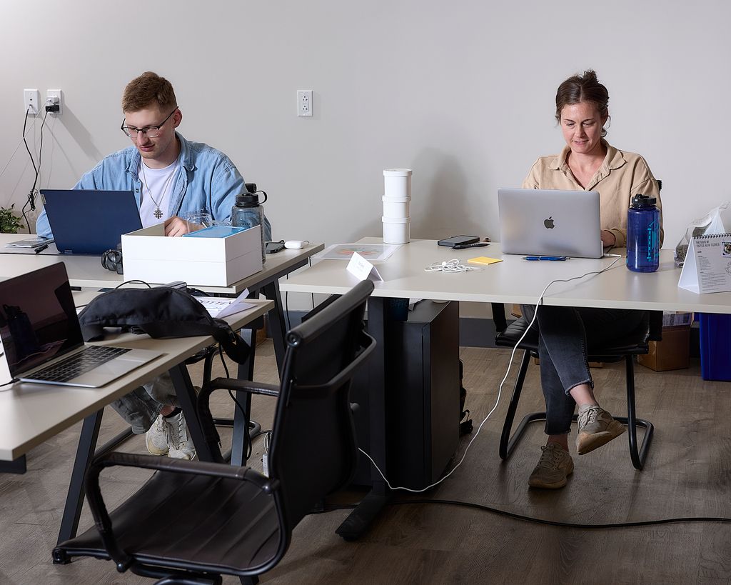 Two Blueprint employees work on laptops at the roastery.