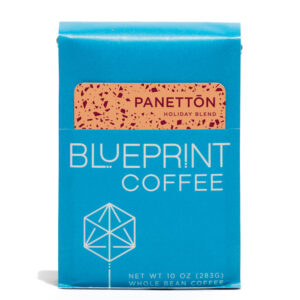 A blue 10-ounce bag of Panettōn Holiday Blend coffee beans featuring the Blueprint Coffee Logo and a removable info card decorated with peach and red flecks.