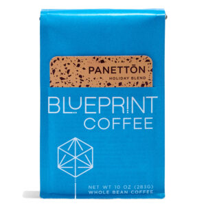 A blue 10-ounce bag of Panettōn Holiday Blend coffee beans featuring the Blueprint Coffee Logo and a removable info card decorated with peach and red flecks.