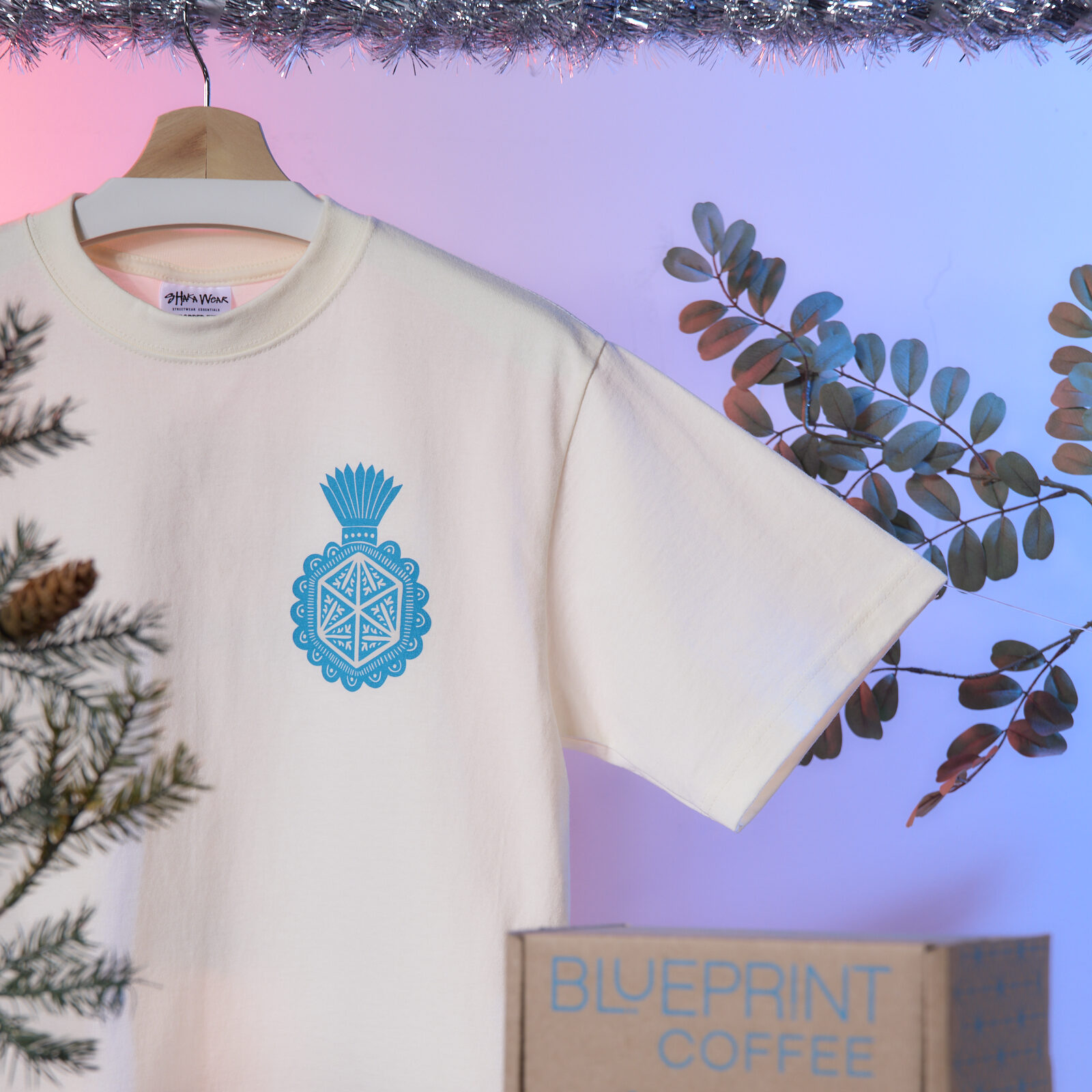 An arrangement includes a screenprinted box with the Blueprint logo and a white t-shirt with a blue screenprinted design.