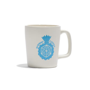 A white ceramic mug screenprinted with a blue illustrated "milagro" design