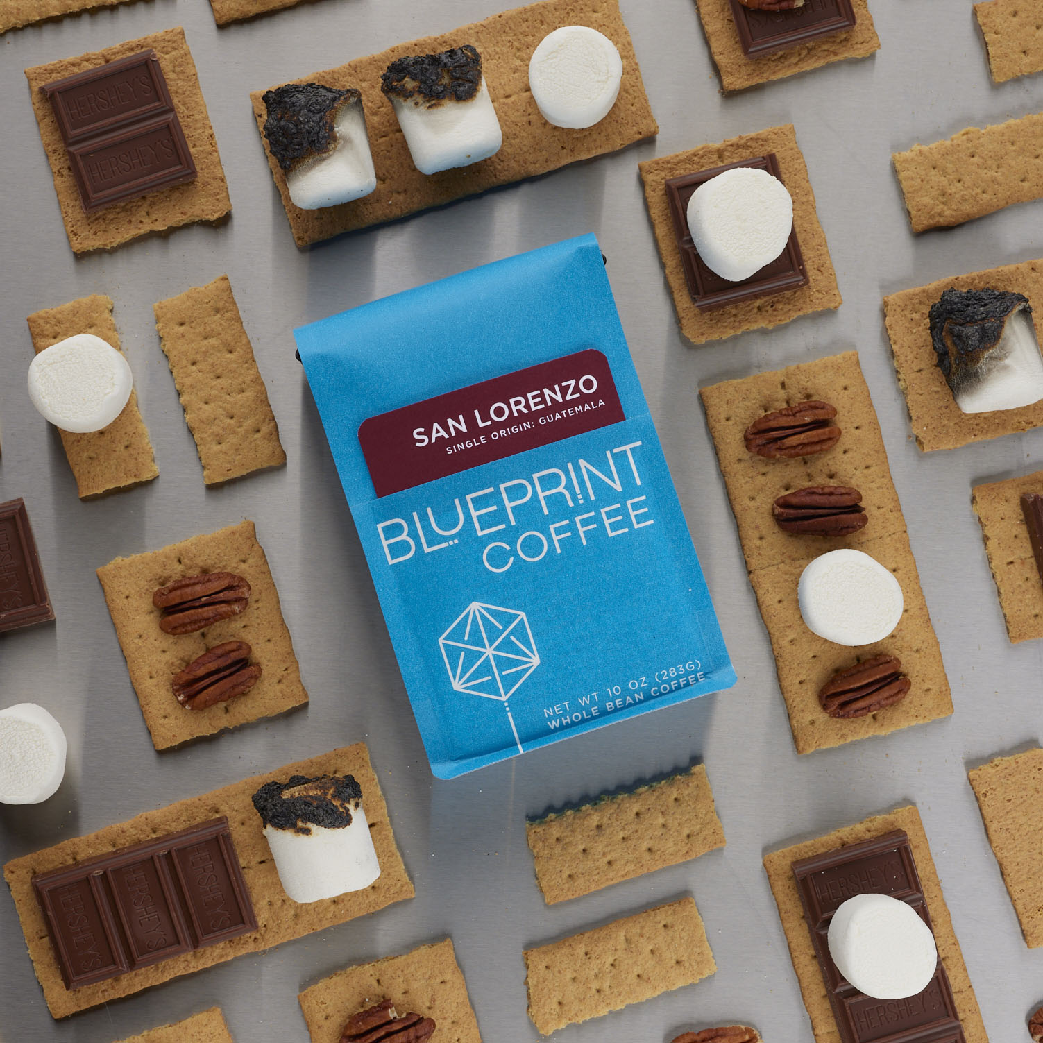 A blue 10-ounce bag San Lorenzo, Guatemala laid flat with an arrangement of graham crackers, toasted marshmallows, chocolate, and pecans surrounding it